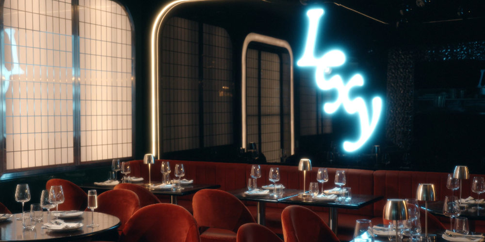 Interior of Lexy Restaurant & Bar on Flinders Lane, Melbourne. Plush red velvet seating, sleek panelled walls, neon βLexyβ sign, and elegantly set tables with wine glasses and lamps create a glamorous fine dining atmosphere perfect for groups and celebrations.