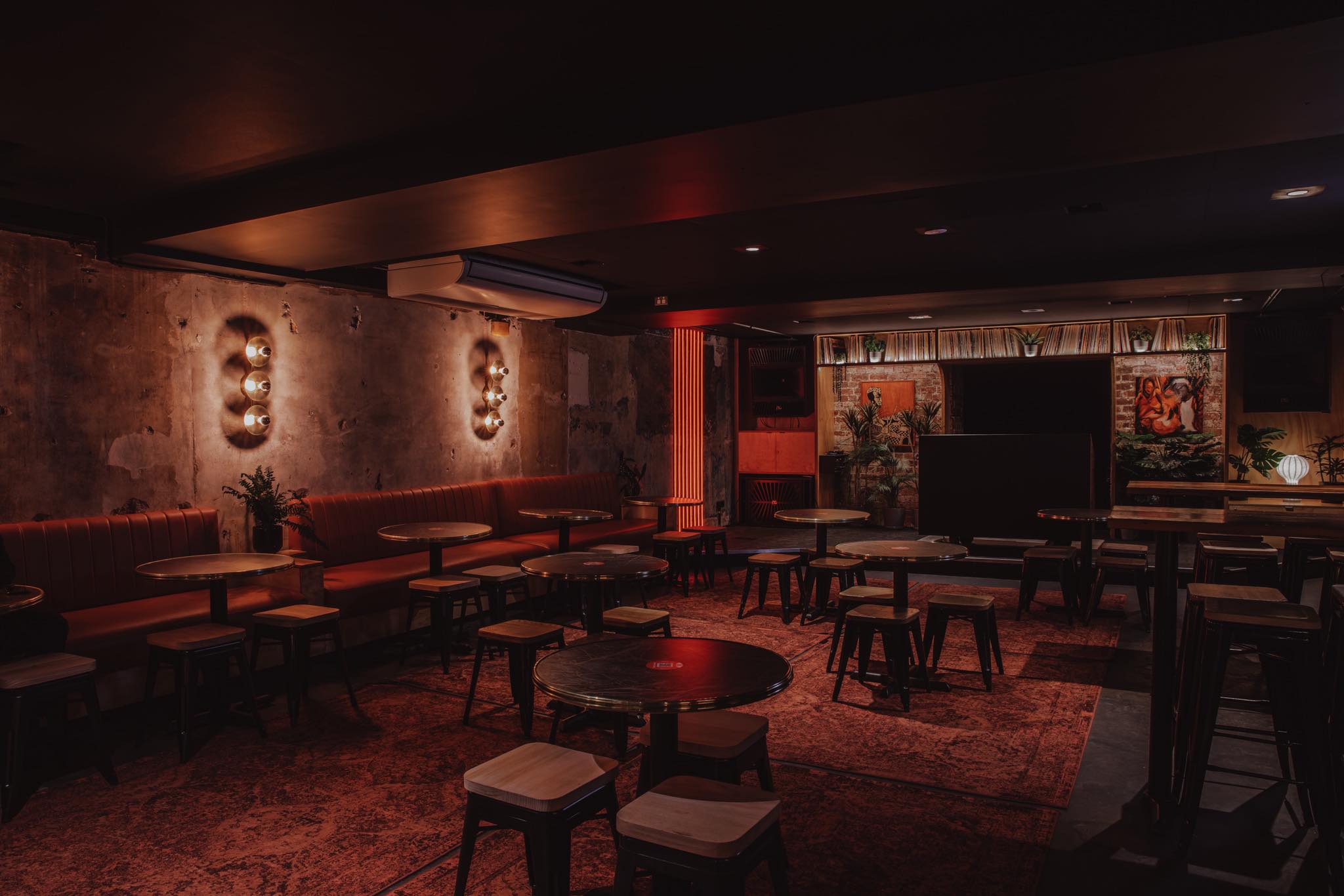 Ambient interior of Wax Music Lounge in Melbourneβs CBD, showcasing its dim red lighting, exposed concrete walls, vintage rugs and intimate tables in a basement on Flinders Street. The photo captures the underground barβs industrial-chic design, curated lighting, and record-lined stage area that embodies the venueβs Melbourne nightlife and live music culture.